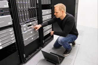 It engineer or consultant working with laptop and maintaining servers in data center.